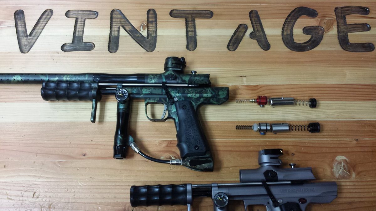 An Empire pump in mottled camouflage anodizing with two valve and spring assemblies laid out beside it.